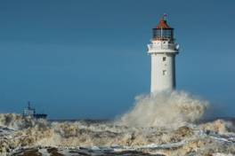 A lighthouse crashing into the water with Crisp Point Light in the background AI-generated content may be incorrect.