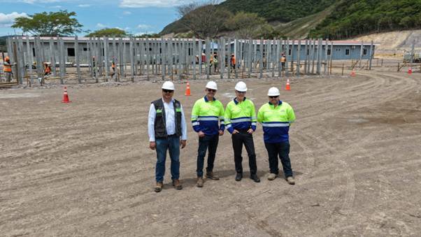 A group of men wearing hard hats and standing in a dirt field AI-generated content may be incorrect.