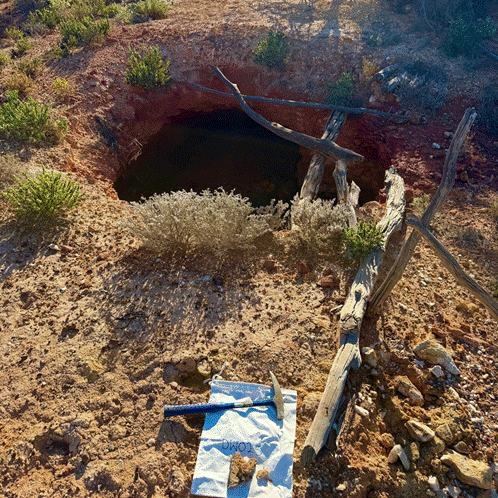 A hole in the ground with a shovel and a wooden fence AI-generated content may be incorrect.