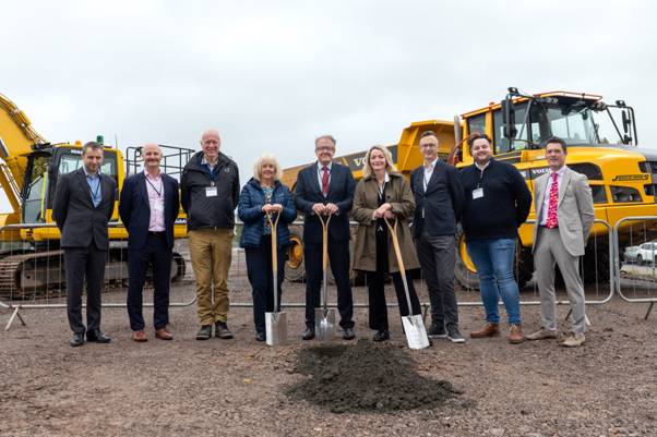 A group of people holding shovels in front of construction equipment AI-generated content may be incorrect.