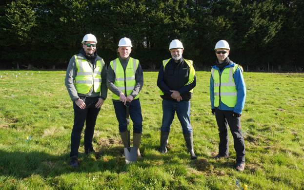 A group of men wearing safety vests and helmets standing in a field AI-generated content may be incorrect.