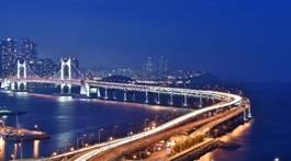 A bridge over water with lights at night AI-generated content may be incorrect.