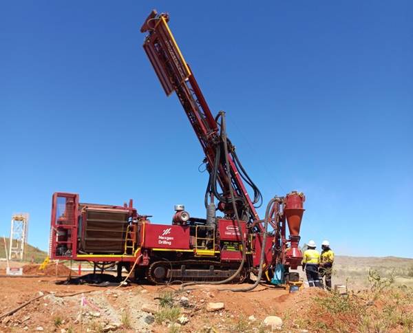 A red drilling rig is operating on a construction site under a clear blue sky. AI-generated content may be incorrect.