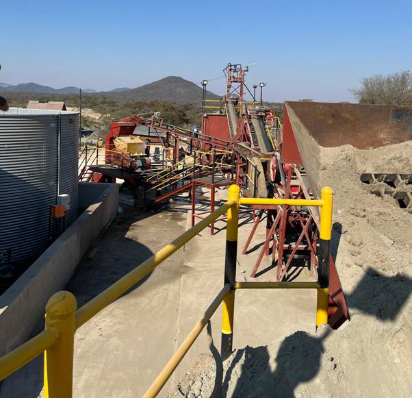 The image shows a large, industrial-scale mining operation with a conveyor belt system, red machinery, and a yellow safety barrier. AI-generated content may be incorrect.