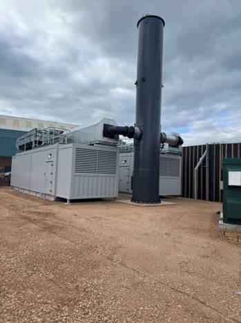 The two Caterpillar G3520K genset enclosures and exhaust stack